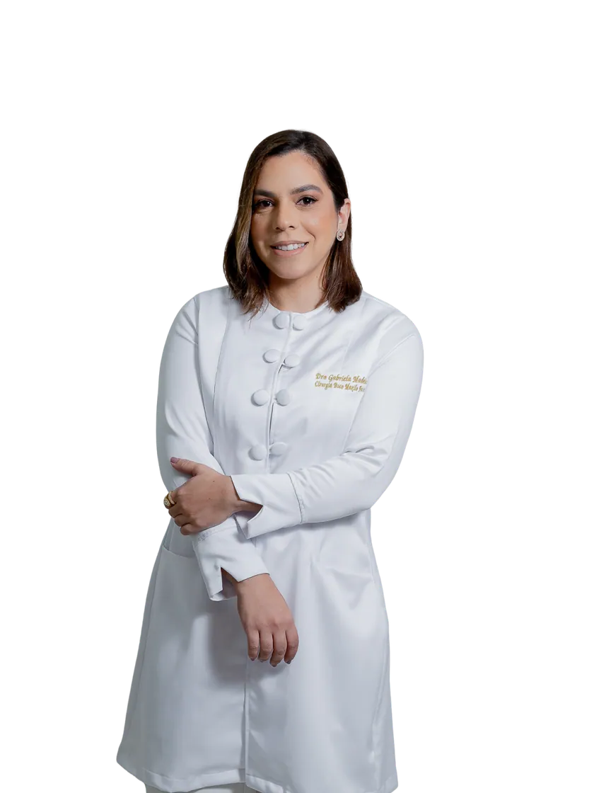 Dra. Gabriela Madeira de jaleco branco, sorrindo, de braços cruzados
