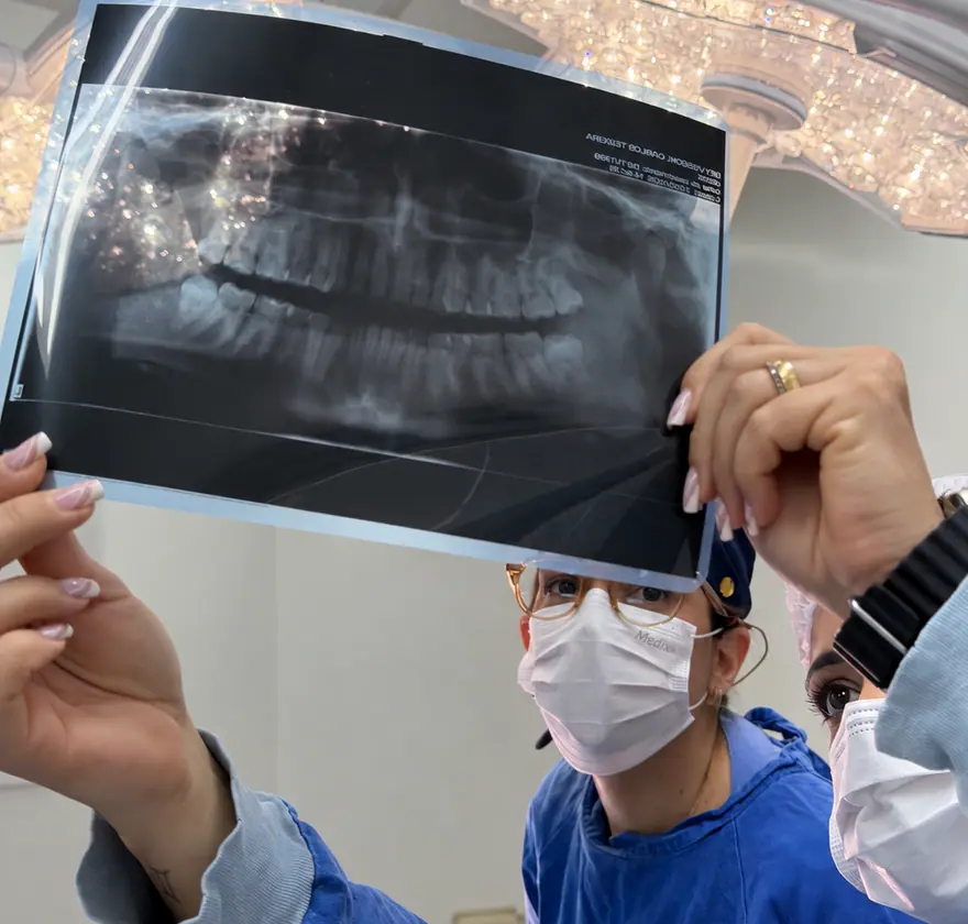 Dra. Gabriela e a equipe analisando uma radiografia panorâmica no centro cirúrgico